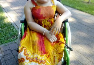 Kobieta na wózku inwalidzkim na dworze w sukience i kapeluszu