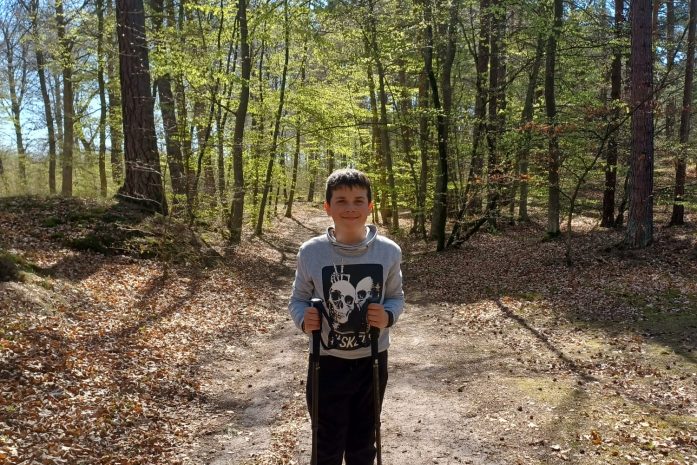 chłopiec w lesie trzymający kije do nordicwakingu